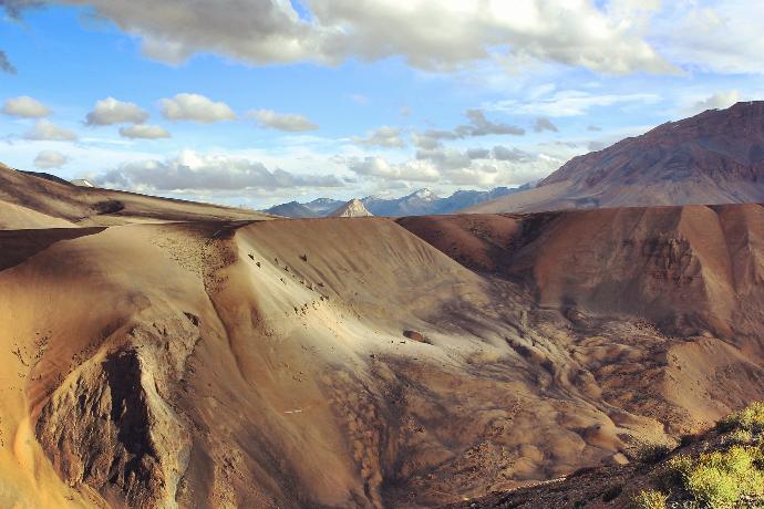 montaña rocosa marrón bajo nubes blancas durante el día